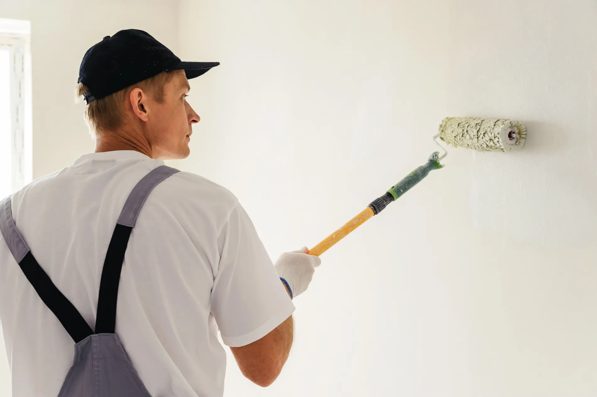 Artisan peintre appliquant la première couche de peinture sur un mur